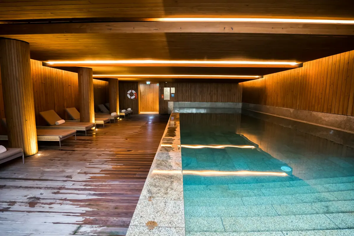 Piscina interior con paredes de madera y luz cálida